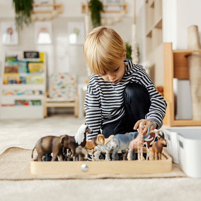 Kleiner Junge spielt mit Spielzeug im Kinderzimmer